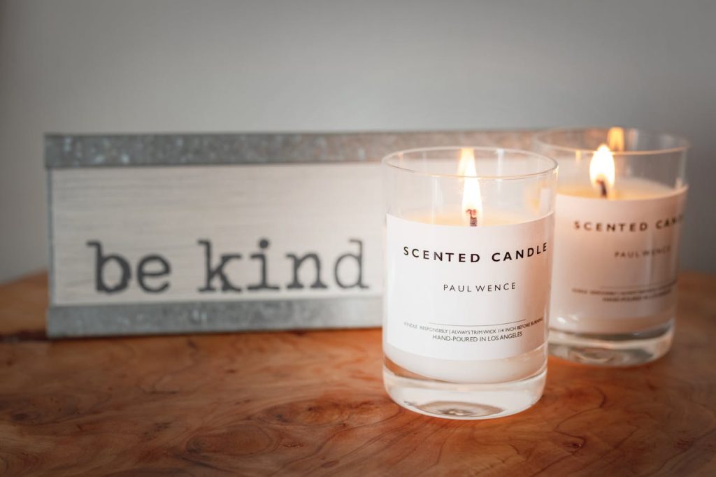 A warm setting with lit scented candles and a motivational be kind sign for a cozy ambiance.
