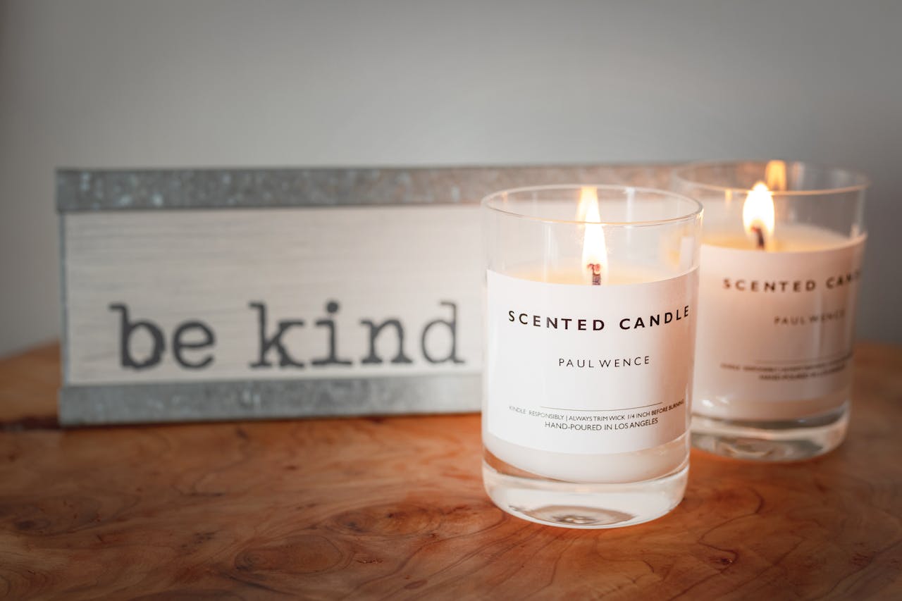 A warm setting with lit scented candles and a motivational be kind sign for a cozy ambiance.